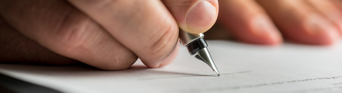 Close up of hand holding ink pen signing a document