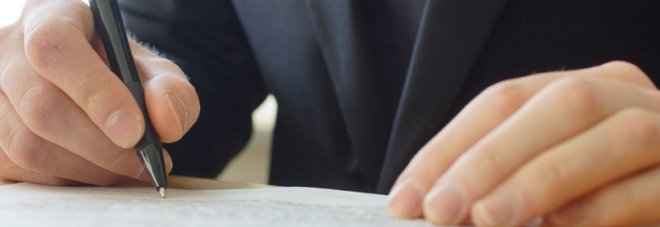 Close up of person signing a document
