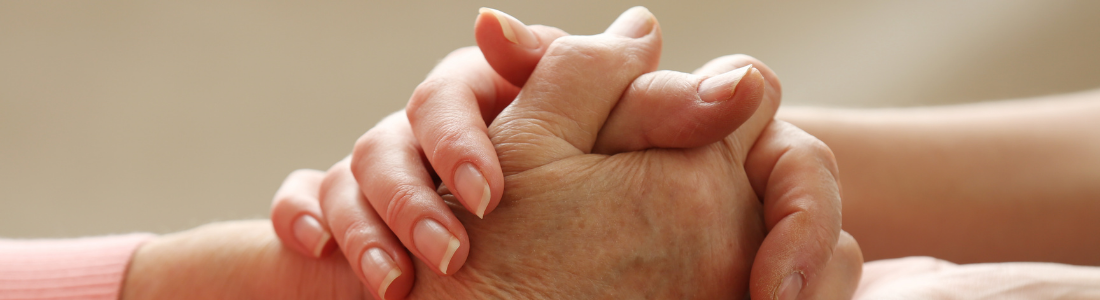Younger hand holding elderly hand