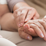 Carer holding the hand of an elderly person