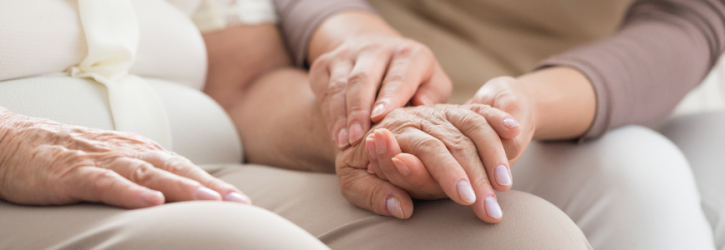 Carer holding the hand of an elderly person