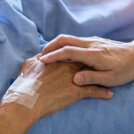 Holding elderly hand on deathbed