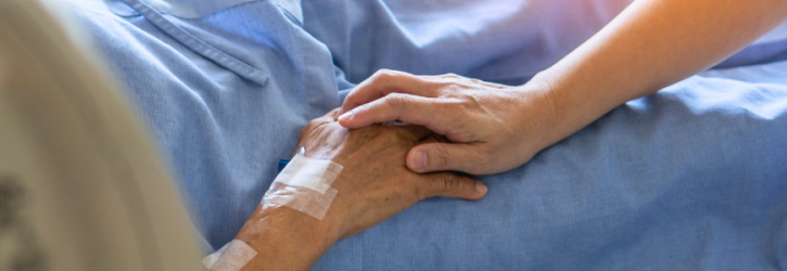 Holding elderly hand on deathbed