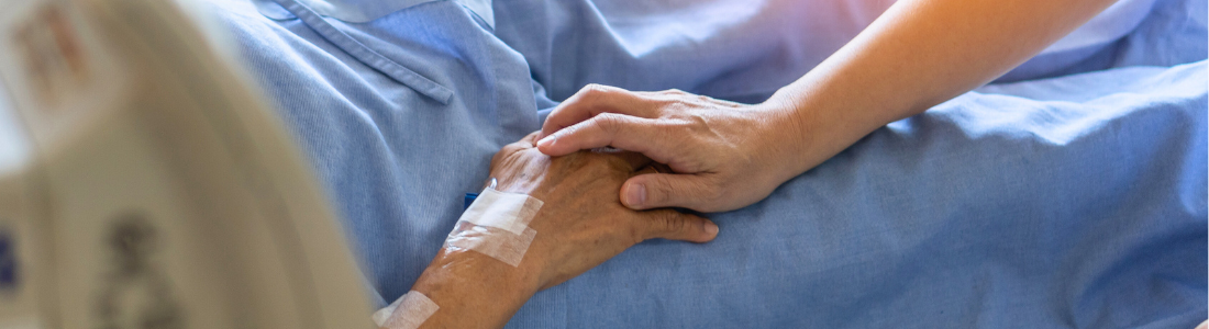 Holding elderly hand on deathbed